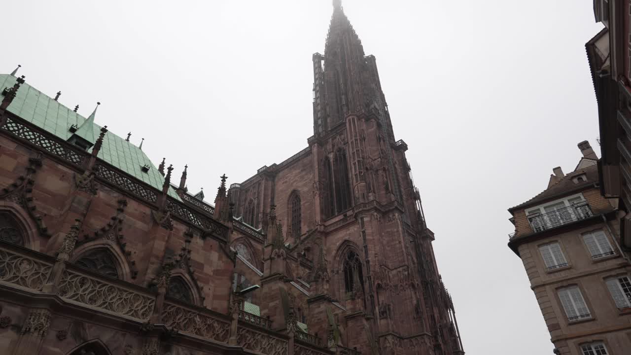 Vista sulla Cattedrale di Strasburgo su uno sfondo di cielo nuvoloso, la torre si erge fiera, affiancando l'ingresso e offrendo uno scorcio dello splendore che si cela all'interno