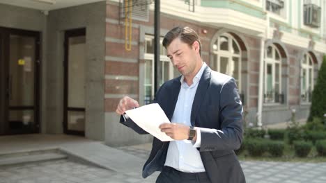 Portrait-businessman-reading-documents-outdoor.-Man-studding-papers-at-street