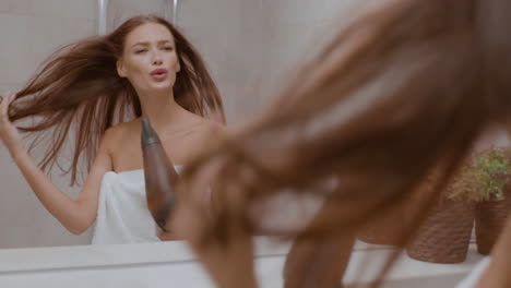 mujer secándose el cabello en el baño