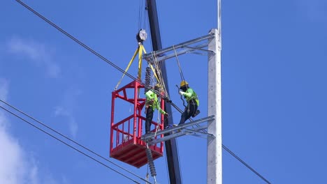 utility workers installing/repairing high voltage power lines with crane
