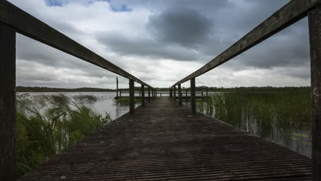 Lapso-De-Tiempo-De-Un-Viejo-Embarcadero-De-Madera-Que-Conduce-Al-Lago-Local-En-El-Paisaje-Rural-De-Irlanda