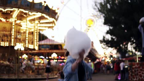 A-happy-young-girl-jumps-up-into-the-air-spreading-her-hands.-She-holds-in-her-hand-sweet-cotton-wool.-Wearing-glasses