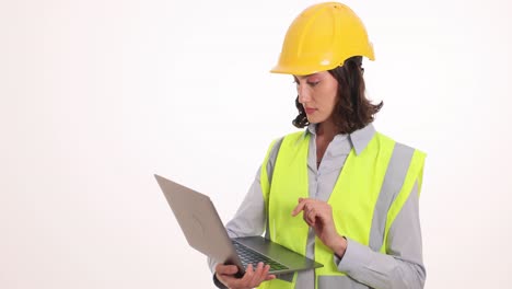female engineer in hard hat and safety vest using laptop