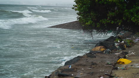 Environmental-issue-with-waves-crashing-into-sea-wall-littered-with-rubbish