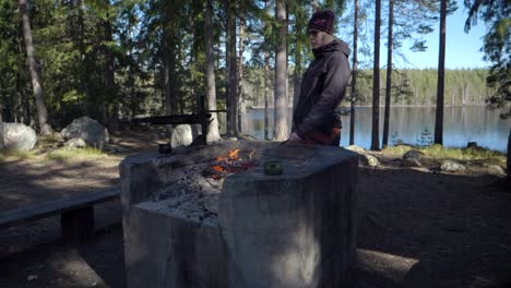 Eine-Wanderin,-Die-Einen-Hot-Dog-Am-Lagerfeuer-Vor-Einem-Kleinen-See-Grillt