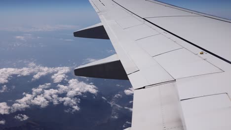 looking outside a window of an aircraft cabin: white airplane wing and clouds