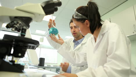 Science-students-looking-at-blue-chemical