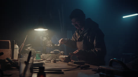 a bombmaker assembles a bomb in his workshop at night