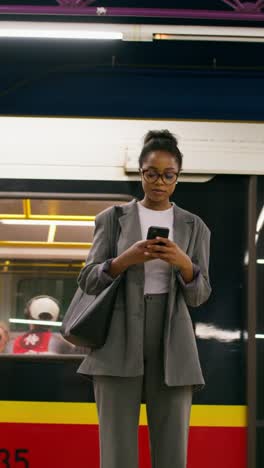 woman using phone in a subway station