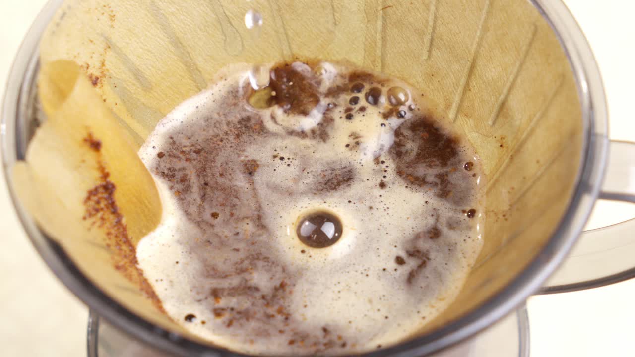 Pouring hot water into a cup with coffee and a filter. Close up