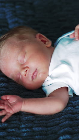 lovely tiny baby boy in white bodysuit. adorable newborn sleeping tight on the blue blanket. vertical video