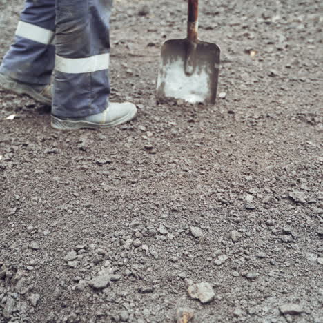 legs of workers in protective uniform and boots with shovels leveling up the road. team of workers preparing the ground for making new asphalt on a street. close-up