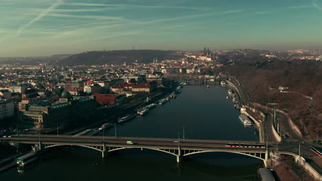 drone-flight-over-prague-vlatava-river-showing-bridges-castle-park-and-buildings-winter-sunshine