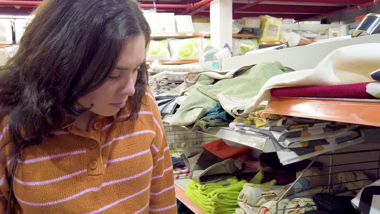 Woman choosing towels and bed linen in home furnishing store