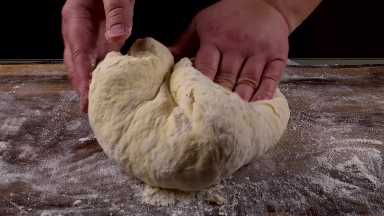 Impastare la pasta su un tagliere di legno con le mani