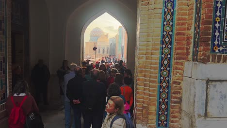 tourists enter a historical mosque or madrasah with intricate tilework