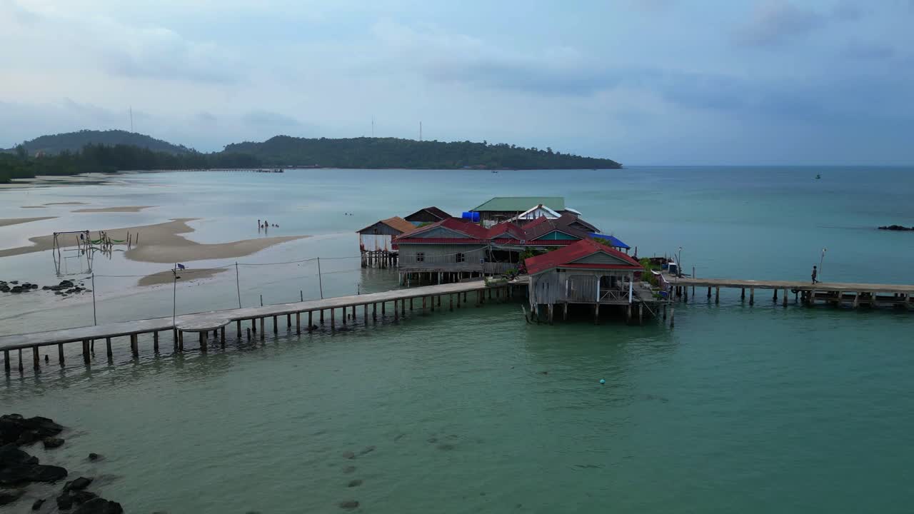 cambodia Koh Rong island, capturing the essence of tropical paradise with its lush palm trees, vibrant turquoise waters, and traditional stilt houses. Unique aerial view flight pull in drone
