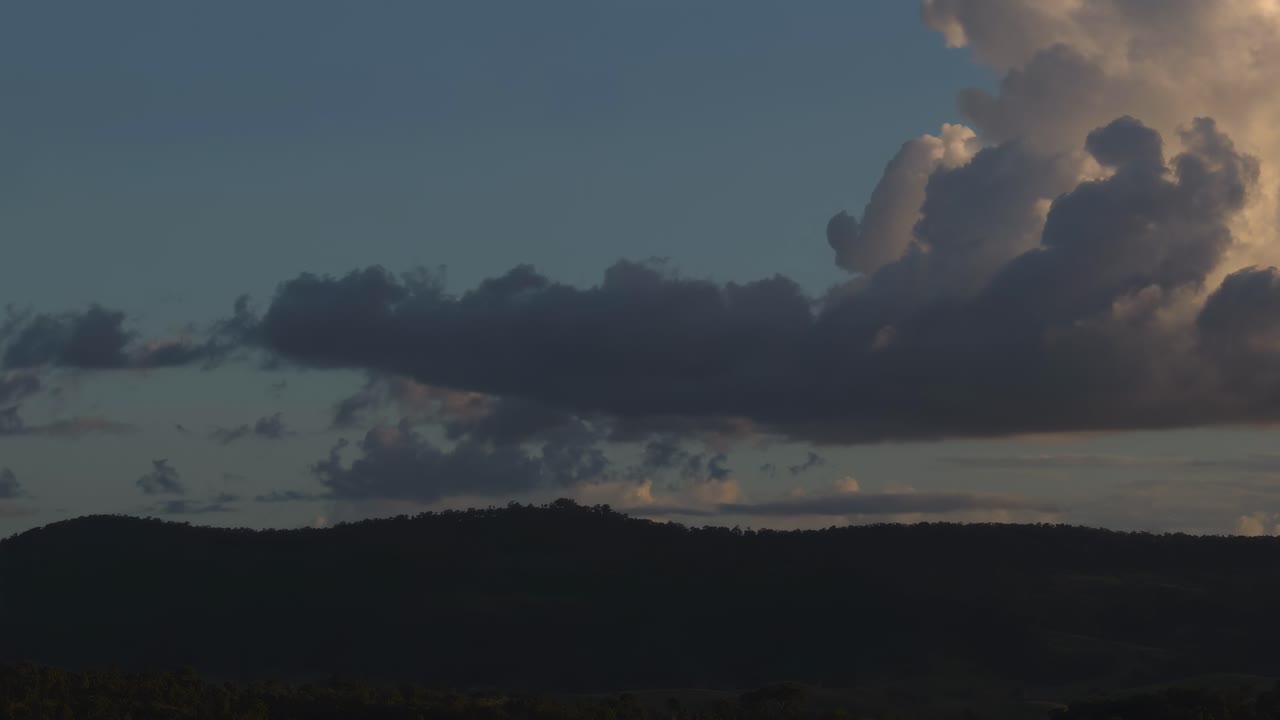 Time-lapse of clouds moving over gently rolling hills during twilight, capturing the serene transition of light.