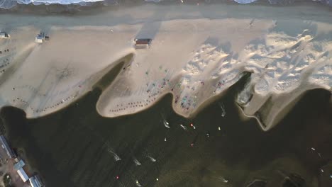 Bird's-eye-drone-shot-of-the-shore-in-Combuco,-Brazil-with-kiteboarders-surfing