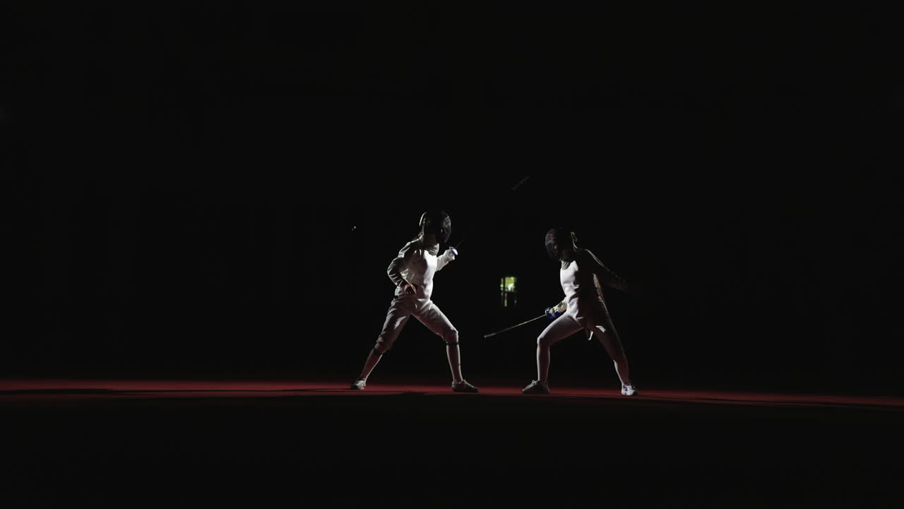 Two fencers compete in a fencing match