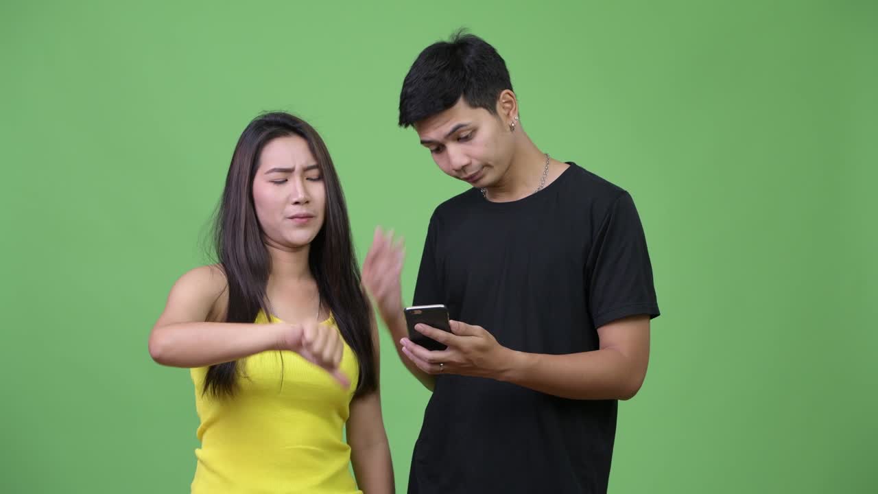 Young Asian couple using phone and getting bad news together