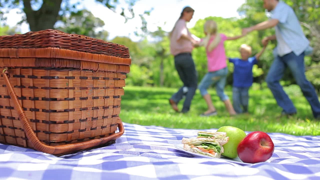 familia juntos en el fondo con un plato en una canasta de picnic en el primer plano