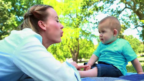 Mother-playing-with-her-baby-son-on-picnic-blanket