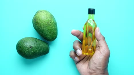 avocado oil in hand with avocados