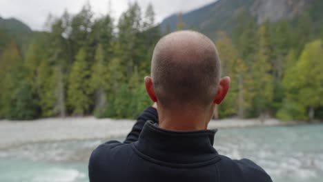 man takes panorama photo on iphone of canadian river