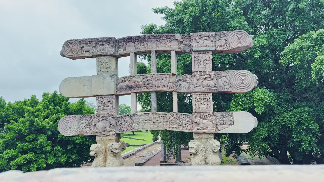 As the camera cranes up, the grand Torana of Sanchi Stupa is revealed, adorned with lions, elephants, celestial beings, and intricate panels narrating Buddhist tales in timeless stone artistry