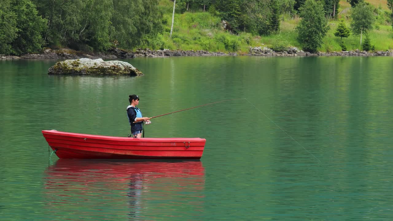 Wanita di perahu menangkap ikan dengan teknik spinning di Norwegia