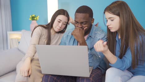 focused group of young people trying to solve a problem. they is looking at the laptop.