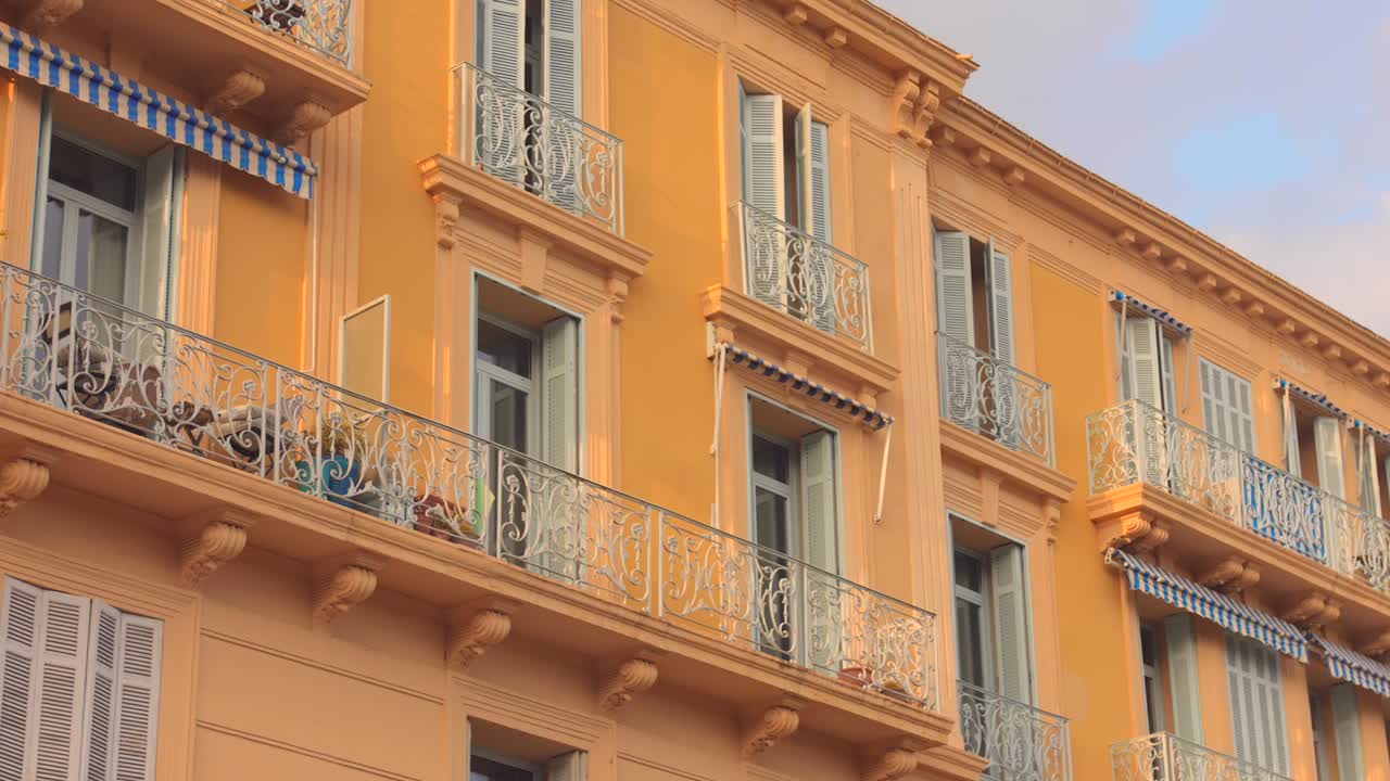 Fachada de prédio de hotel com paredes amarelas vibrantes e varandas decoradas. - Close amplo