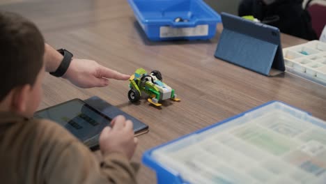 children intently focused on assembling parts from a robotics kit, with a tablet displaying instructions, promoting stem learning and creativity