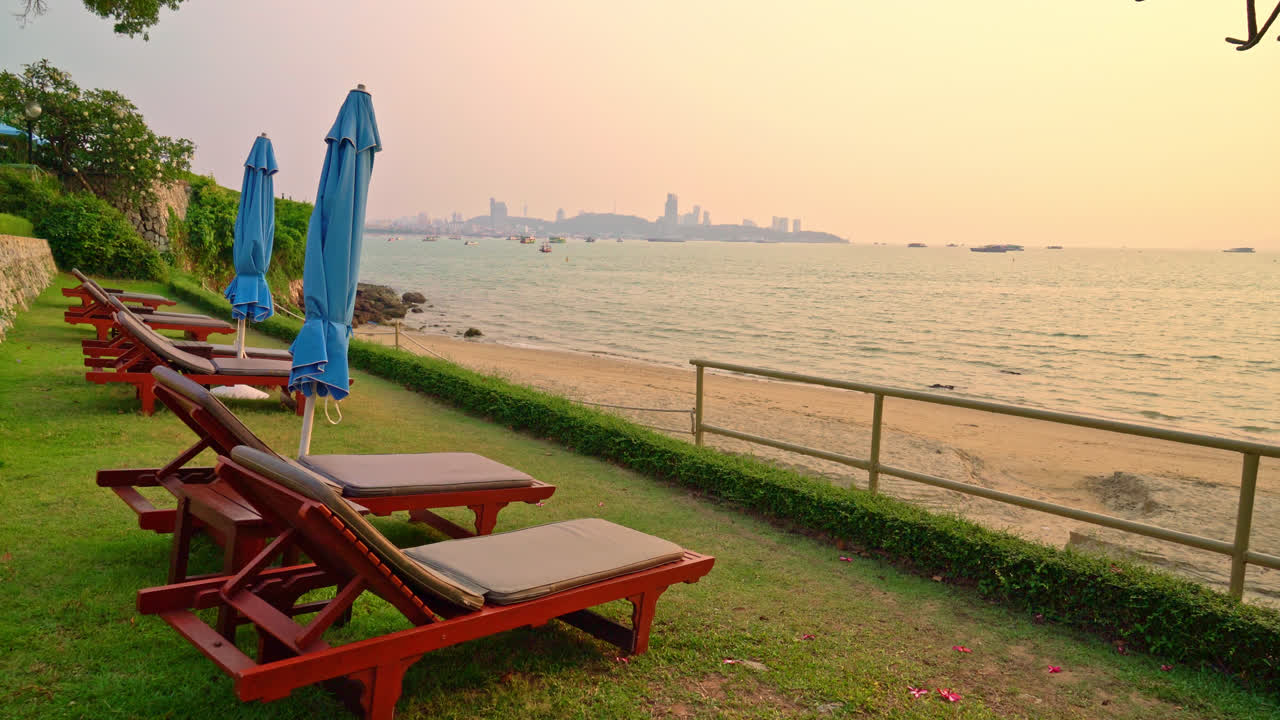 해질녘 바다를 배경으로 한 해변 의자 또는 풀 침대와 파라솔