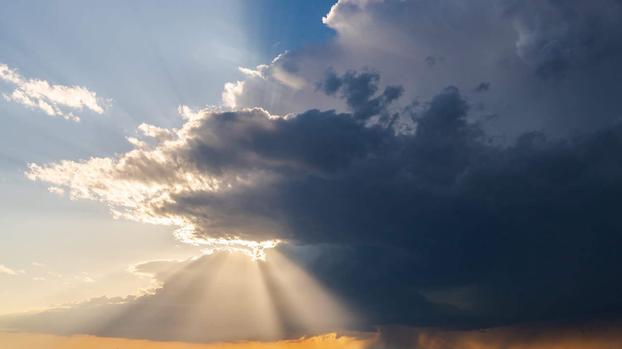 I raggi del sole al tramonto splendono attraverso le nuvole scure di una tempesta in movimento.