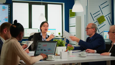 Multi-ethnic-business-team-sitting-at-table-in-office-center-speaking-about-project