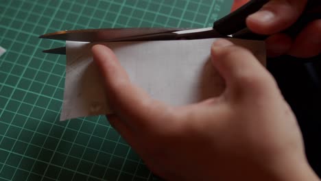 holding a small piece of fabric and cutting it with scissors.