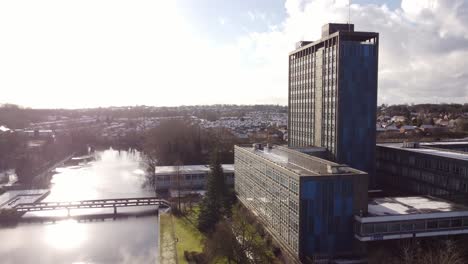 Aerial-view-Pilkington's-glass-head-office-and-lake,-a-modern-blue-high-rise-with-shared-office-space