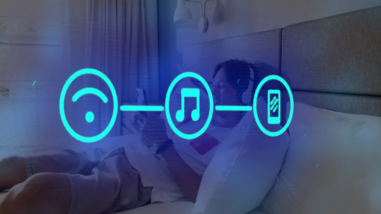 Teen boy reclining on bed, tapping phone, starting holo icons linking Wi?Fi and music streaming