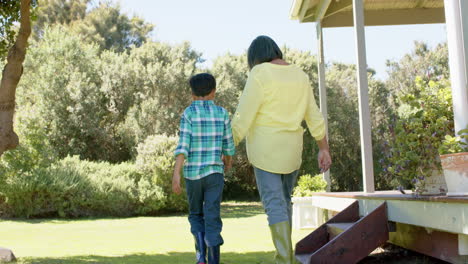 Glückliche-Biracial-Großmutter-Und-Enkel-Beim-Spaziergang-Im-Sonnigen-Garten,-Zeitlupe