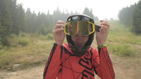 portrait close up of athlete - downhill bike rider putting on his goggles wearing a full face helmet