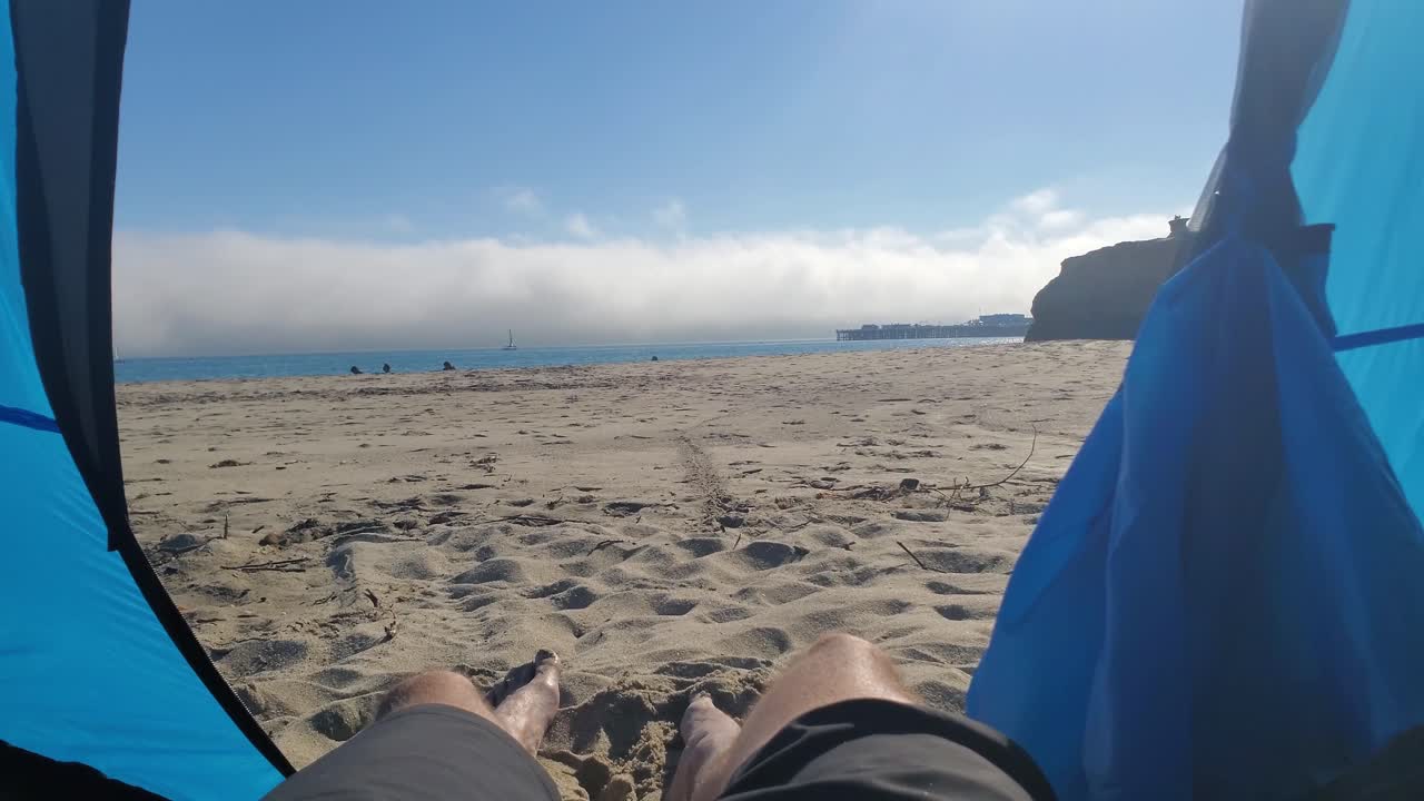 las piernas de un hombre colgando de una carpa disfrutando de la playa sunny beach en santa cruz, california