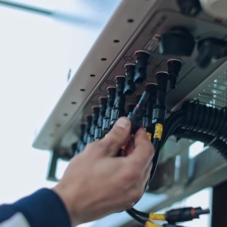 worker's hand connects electrical equipment. electrician connecting black wires on the electrical system outdoors.