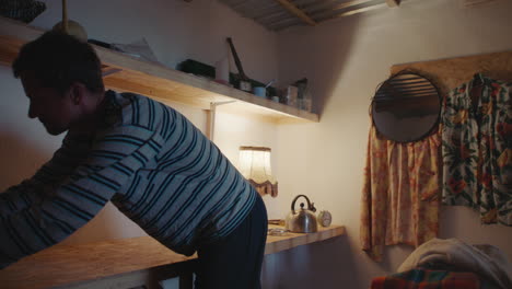 man working on a lamp in a small room at night.