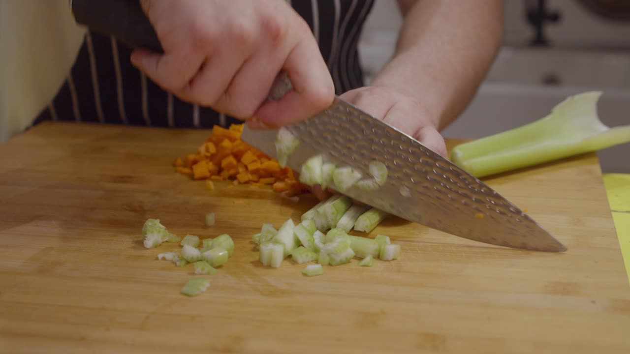 шеф-повар нарезает овощной сельдерей на деревянной разделочной доске