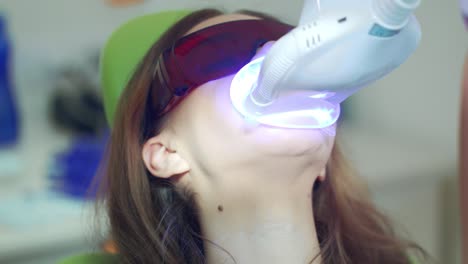 close up woman at teeth whitening procedure in dental office