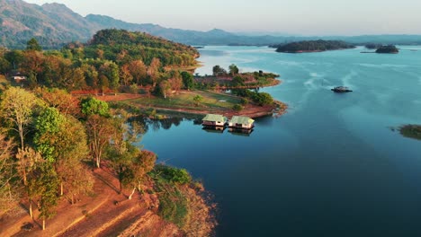 a drone advances over a lake in khao laem national park, capturing typical thai houses in sangklaburi, thailand