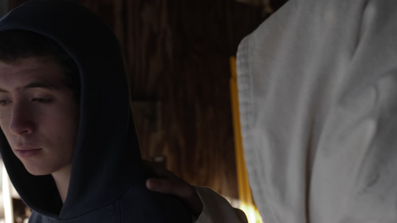 un adolescente mira a jesús, o a un hombre con túnica blanca, mientras coloca su mano sobre el hombro del adolescente para consolarlo