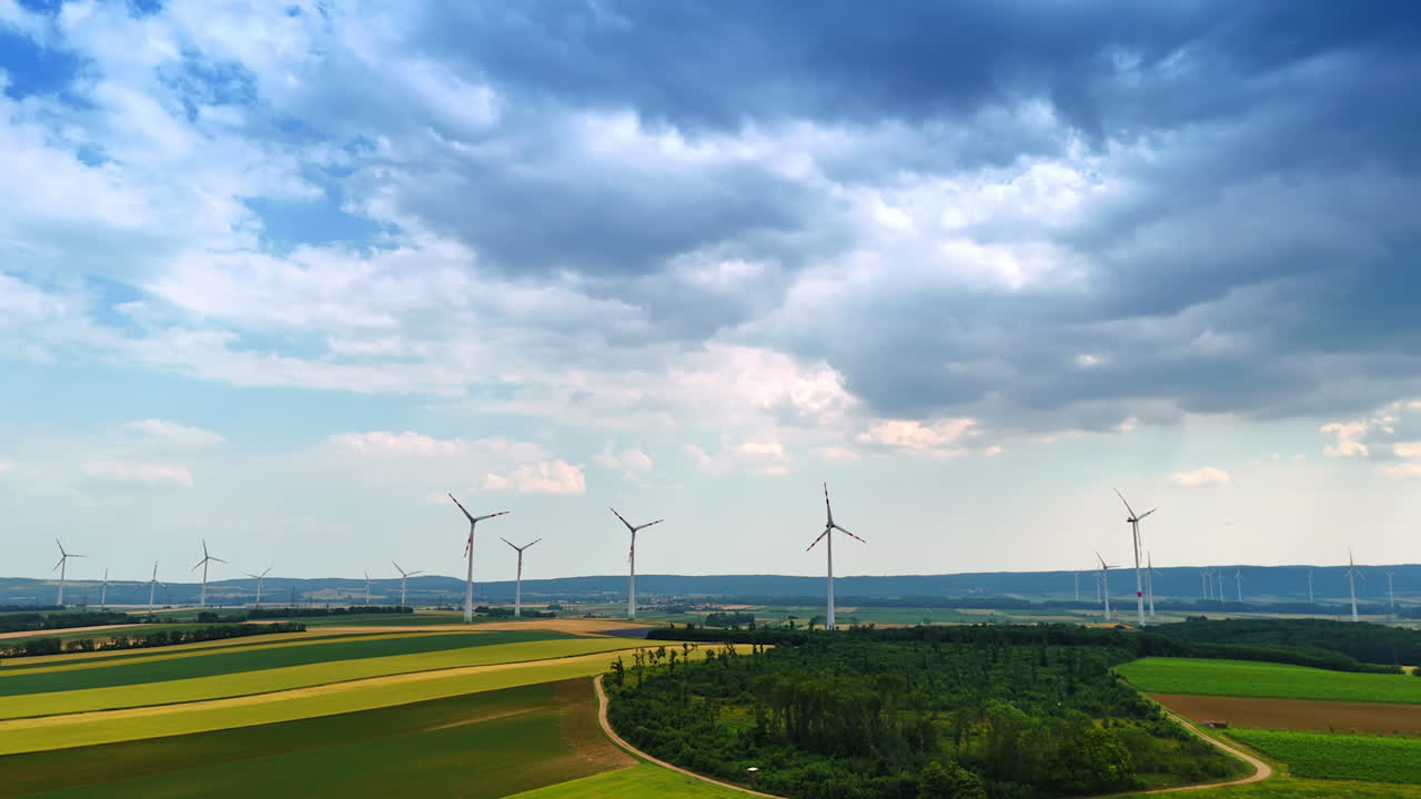 Turbines generating clean energy. Wind turbines stand tall against a cloudy sky above green fields, highlighting renewable energy efforts in rural areas